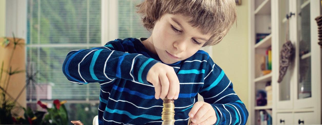Young Boy Concentrating While Counting Stack Of Coins