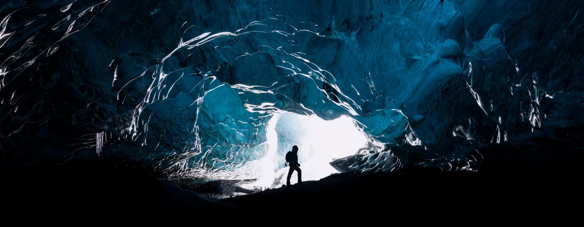 Silhouette Of Man Inside Entrance To Ice Cave