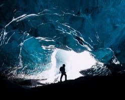 Silhouette Of Man Inside Entrance To Ice Cave
