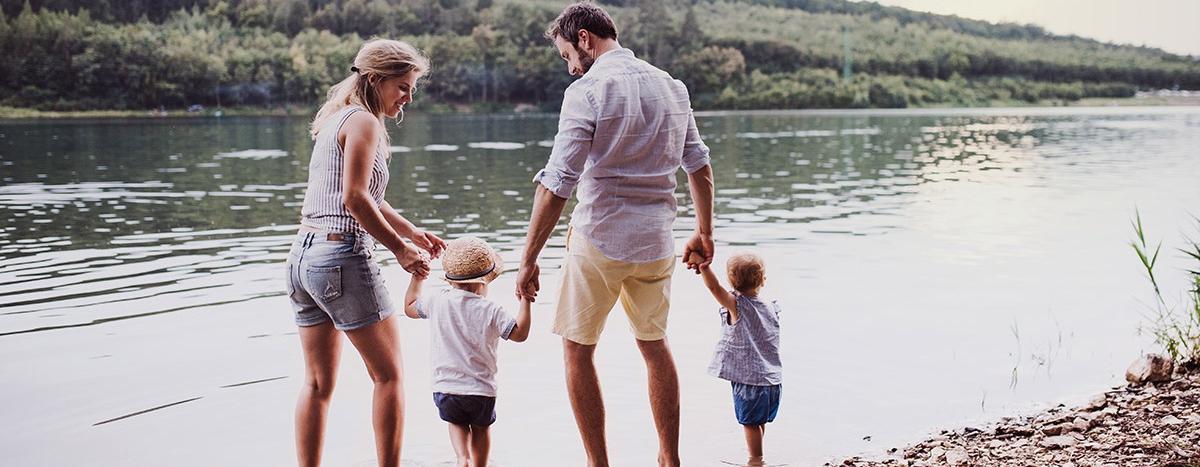 Image of Father and Mother with their 2 Young Children Walking Along a Lake