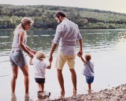 Image of Father and Mother with their 2 Young Children Walking Along a Lake