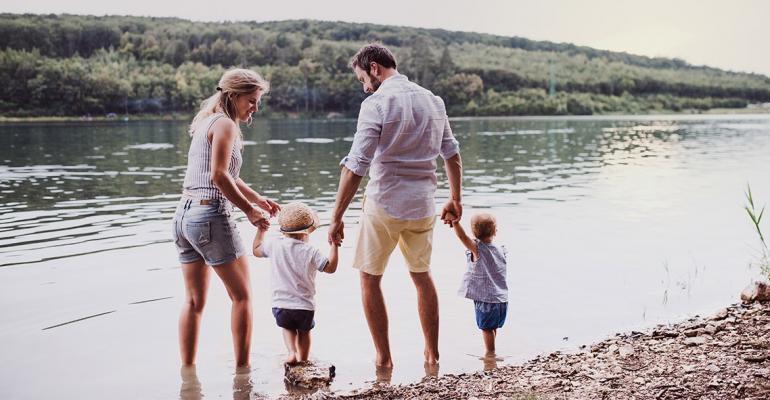 Image of Father and Mother with their 2 Young Children Walking Along a Lake