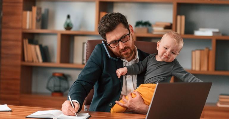 Busy Business Man On Telephone In Front of Computer Holding Baby