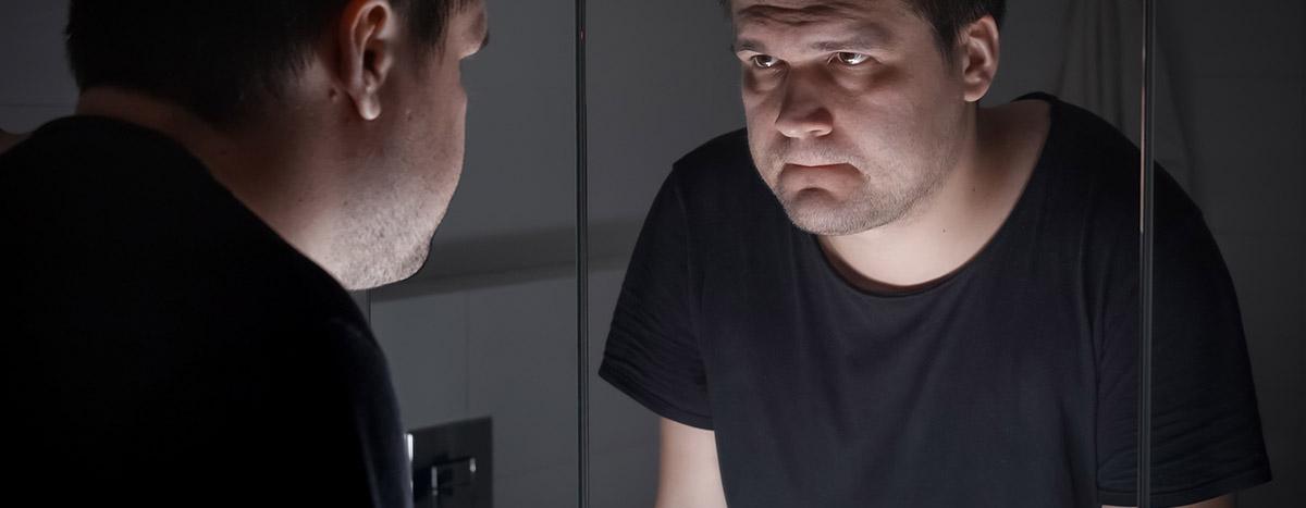 Man in Black T-shirt Looking at Himself in Mirror