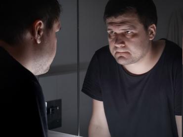 Man in Black T-shirt Looking at Himself in Mirror