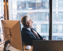 Pensive Man  in Business Office Sitting at Desk Looking Out of Window