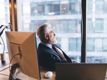 Pensive Man  in Business Office Sitting at Desk Looking Out of Window