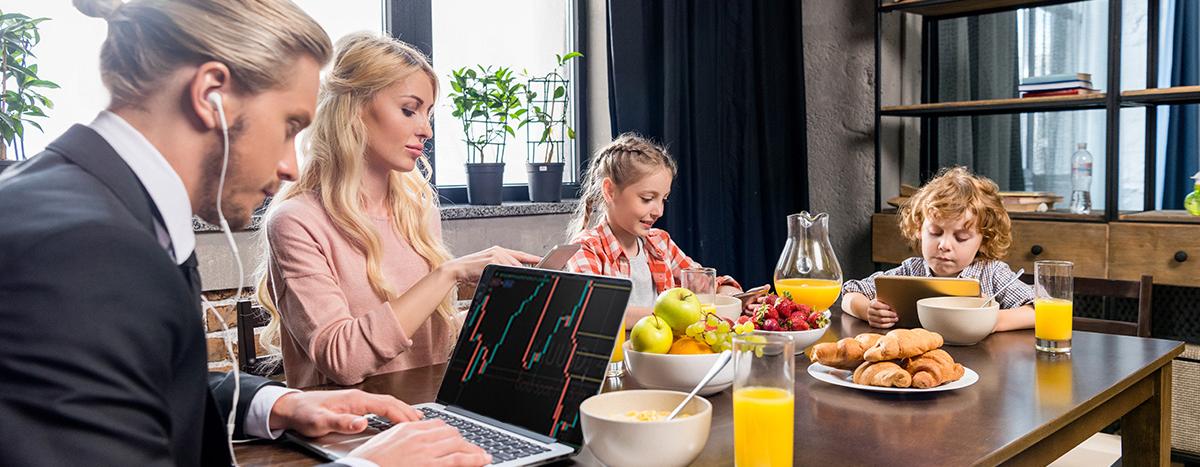 young-businessman-using-laptop-while-having-breakfast-with-family