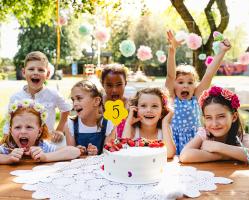 children-with-cake-standing-around-table-on-birthday