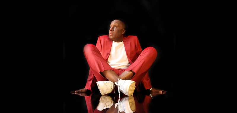 Bruny Surin Sitting Down Posing In Stylish Red Suit