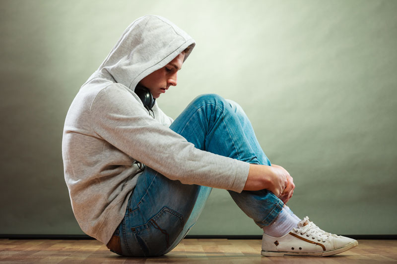 Teenager Sitting In Crouched Position Looking Sad