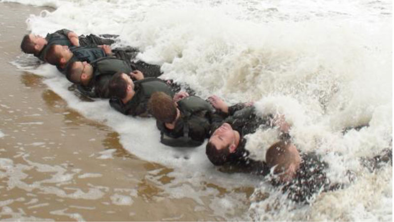 Men Laying Down Being With Water Tide Coming Over Them During Navy Seals infamous Hell Week