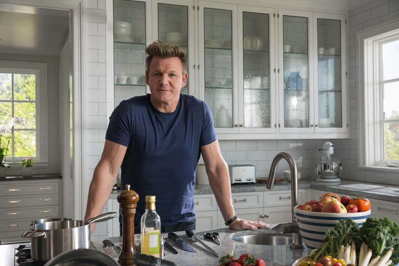 Chef Gordon Ramsey Standing In Kitchen With Hands On Counter