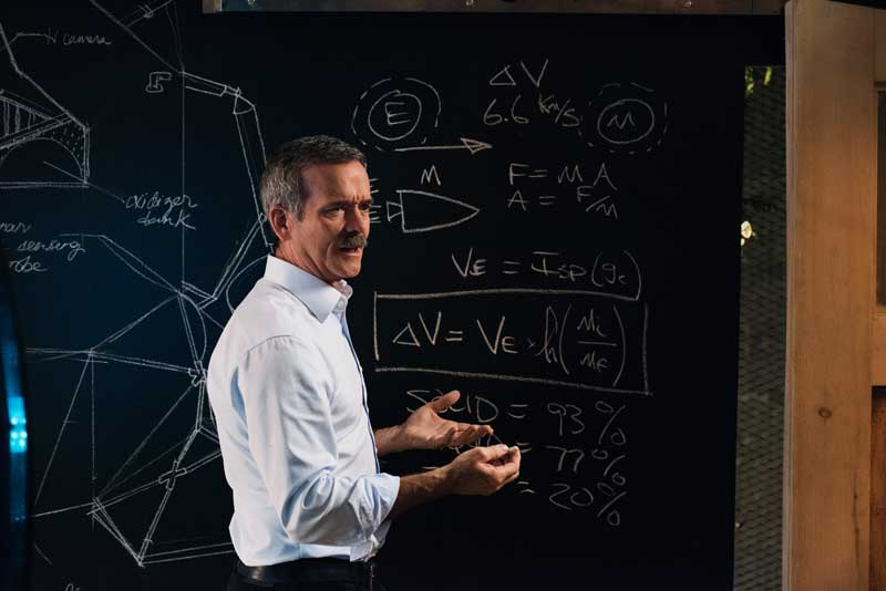 Astronaut Chris Hadfield Speaking In Front of Blackboard With Equations