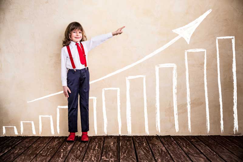 Young Boy With Long Hair Dressed Business Like And Pointing Upwards With Painted Chart And Arrow Behind Him