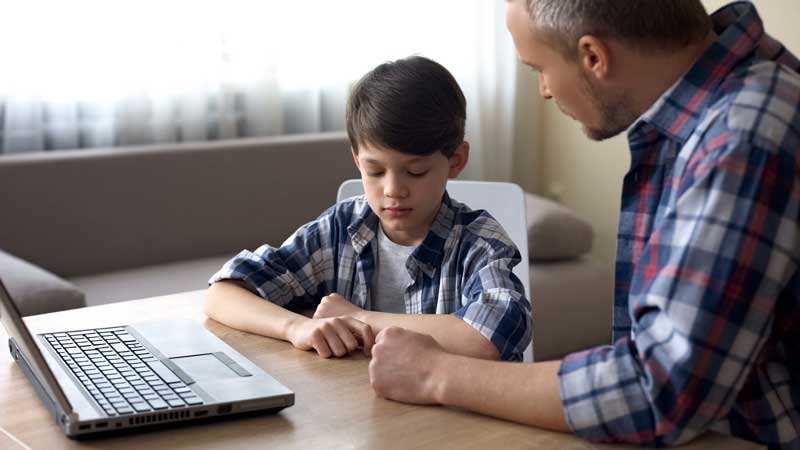 Father Talking To Son Who Seems Sad In Front Of A Computer