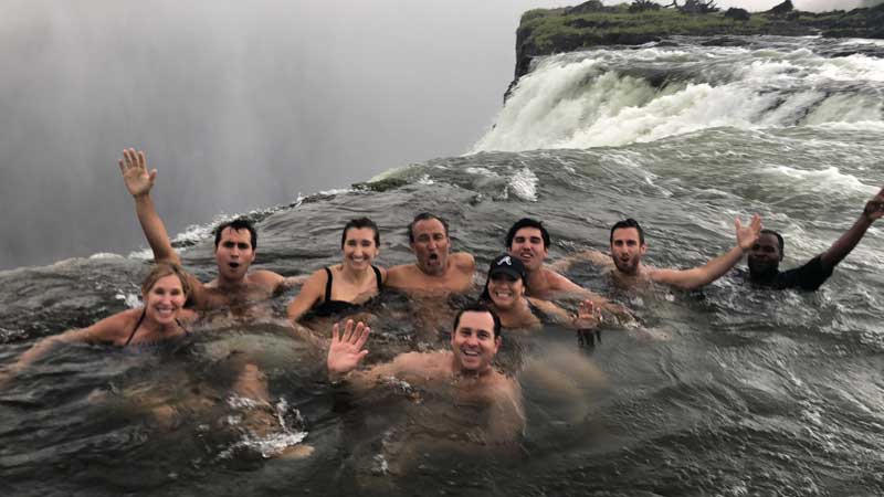 Oscar Munoz And Family Sitting and Waving In The Devils Pool Waterfall In Zambia Africa