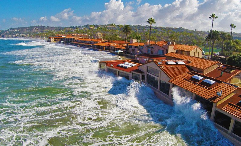 Sky View Of Marine Room On A Sunny Day With Waves Crashing Against Restaurant Windows