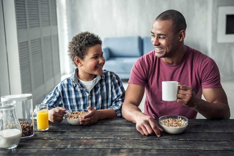 Black Father And Son Sharing A Breakfast And Smiling