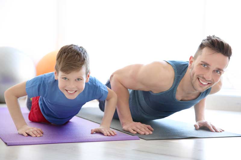 White Father And Son Smiling While Exercising Together