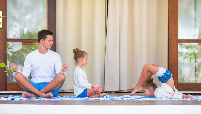 Father Looking At 2 Daughters While Doing Yoga